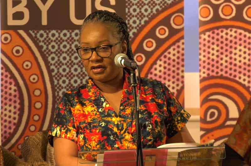 Photo of Rebecca Mbewe speaking in to a microphone at the first our stories told by us book launch